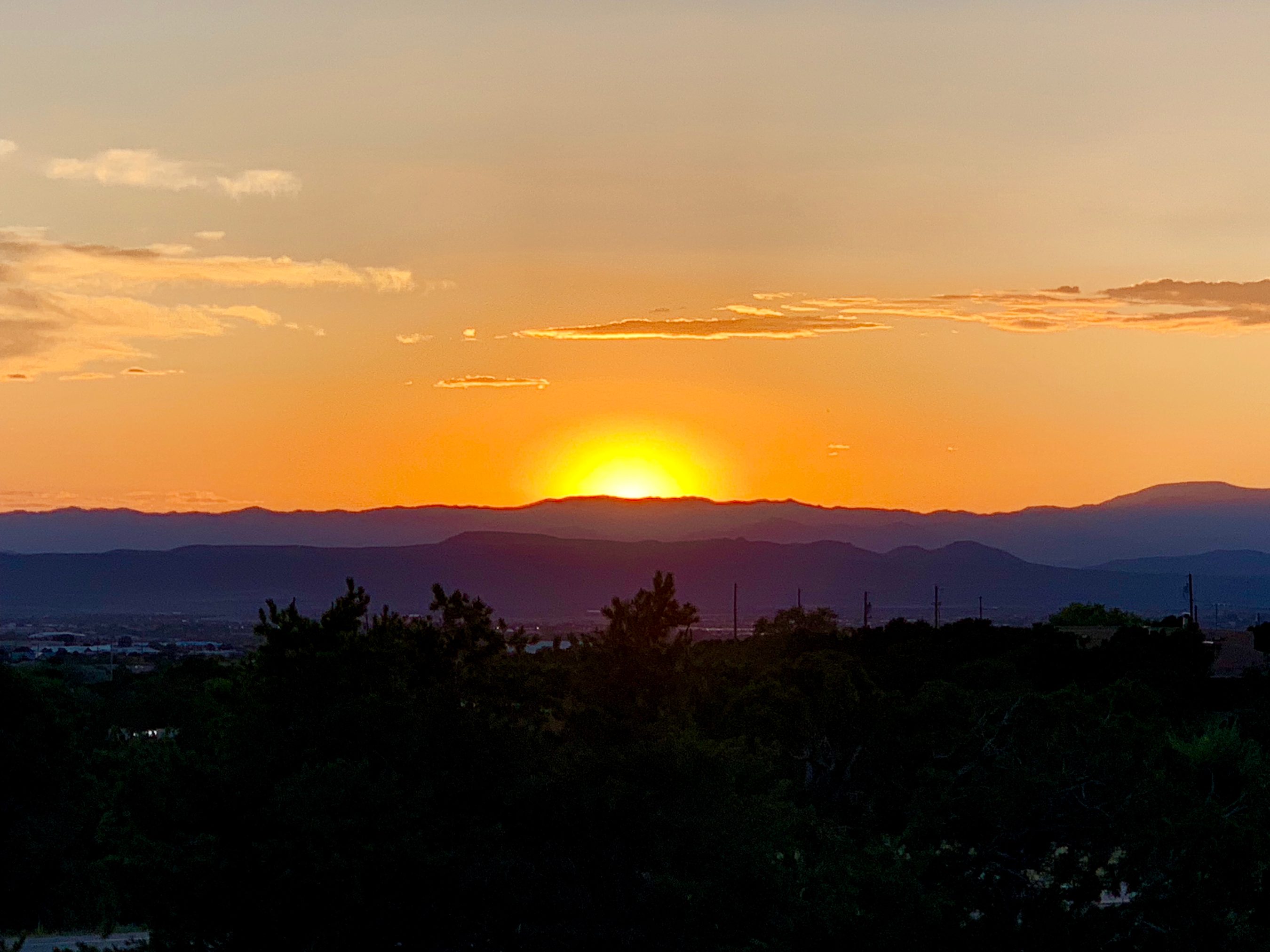 The sun setting over a valley and distant hills