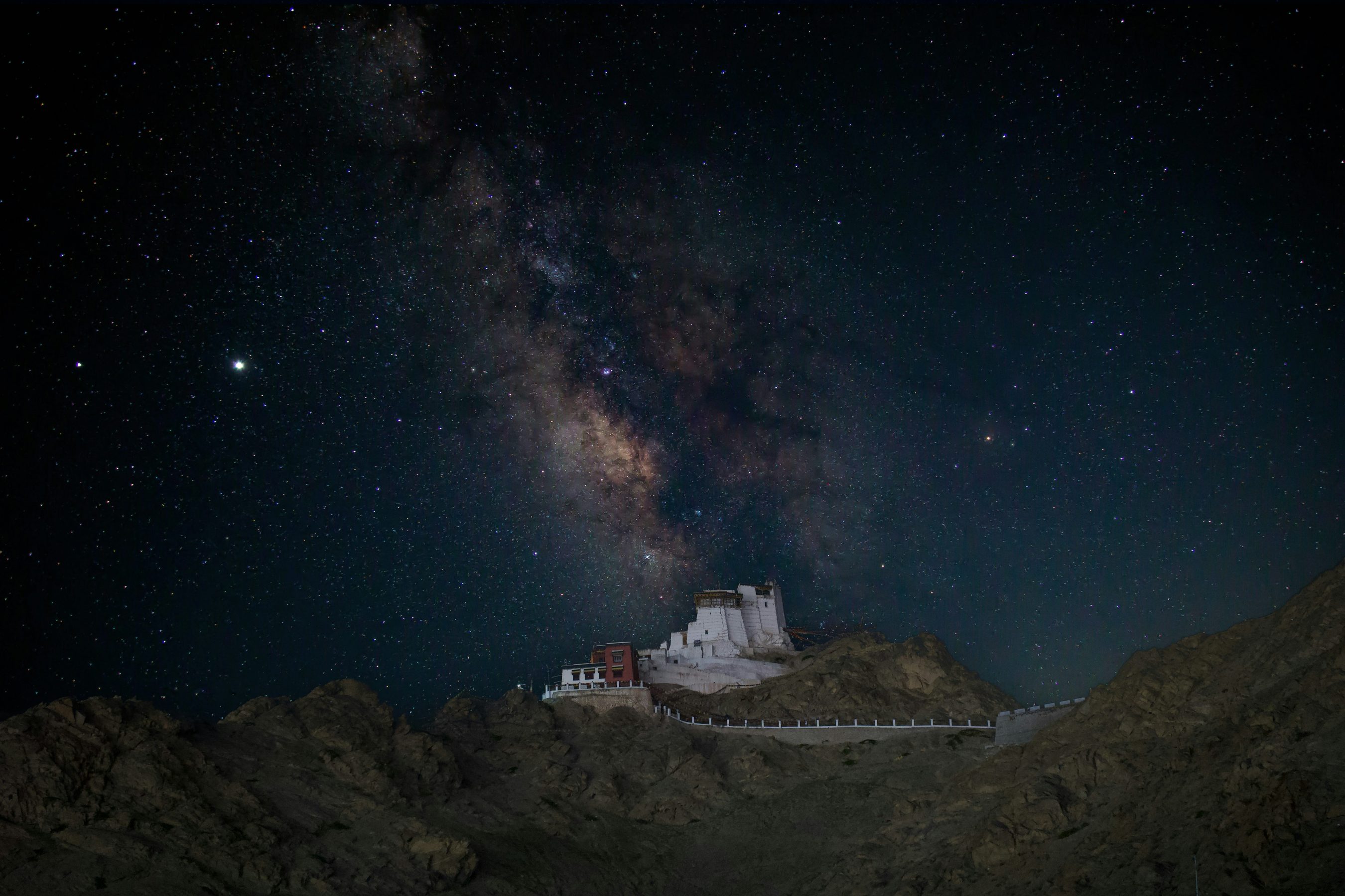 A monastery on a dark ridge under the Milky Way