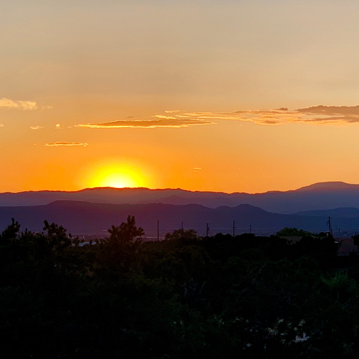 The sun setting over a valley and distant hills