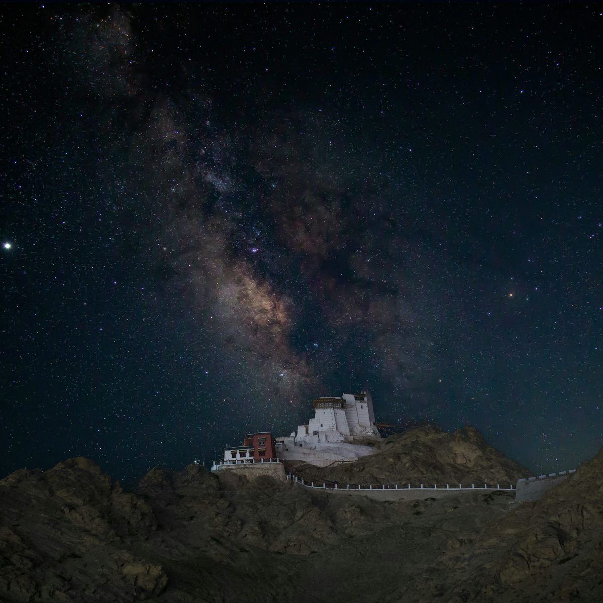 A monastery on a dark ridge under the Milky Way